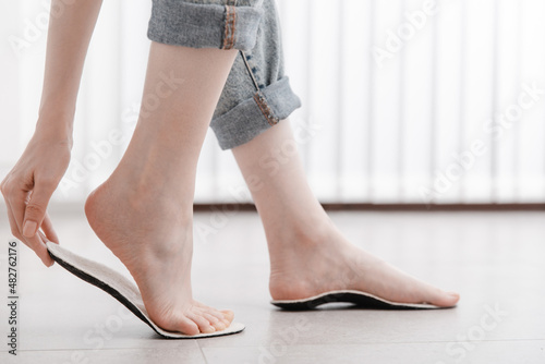 Woman fitting orthopedic insole indoors, close up. Girl holding an insole next to foot at home. Orthopedic insoles. Foot care banner. Flat Feet Correction. Treatment and prevention of foot diseases.