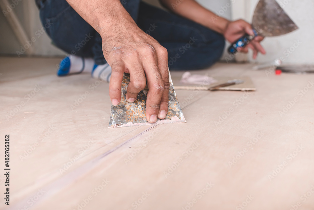A carpenter adds putty with a trowel to fill the gaps between two