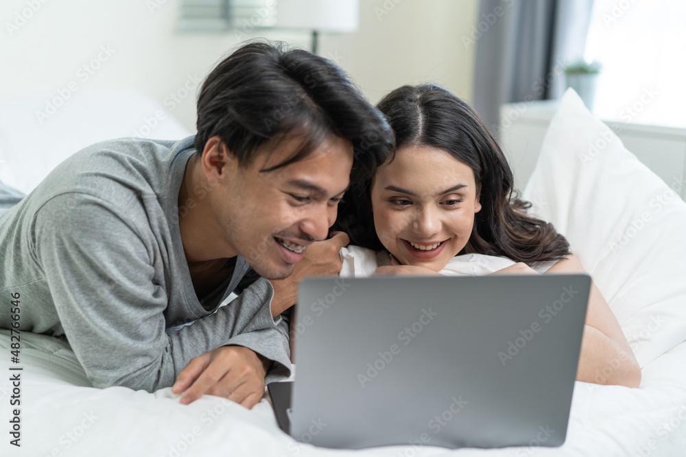 Asian attractive happy young couple watching movie on bed in bedroom. Asian attractive happy young couple watching movie on bed in bedroom.