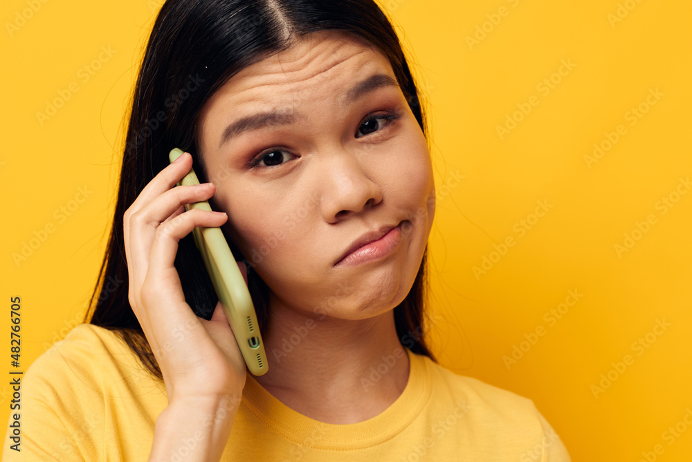 woman with Asian appearance phone communication fun use yellow background unaltered woman with Asian appearance phone communication fun use yellow background unaltered