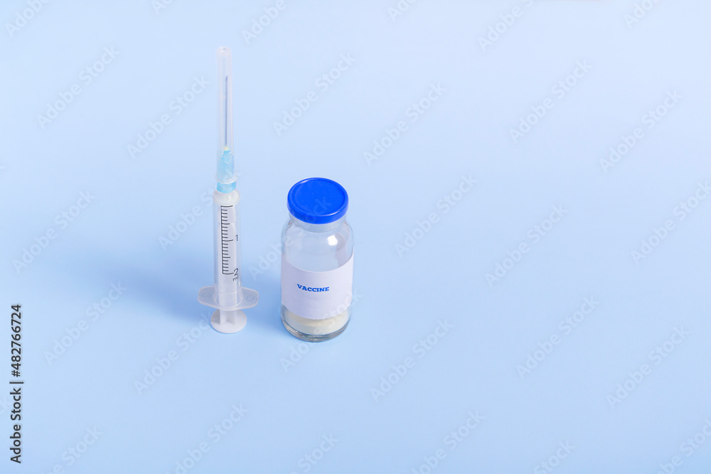 Vaccine for immunization against COVID and a syringe on a colored background. Closeup medical concept Vaccine for immunization against COVID and a syringe on a colored background. Closeup medical concept