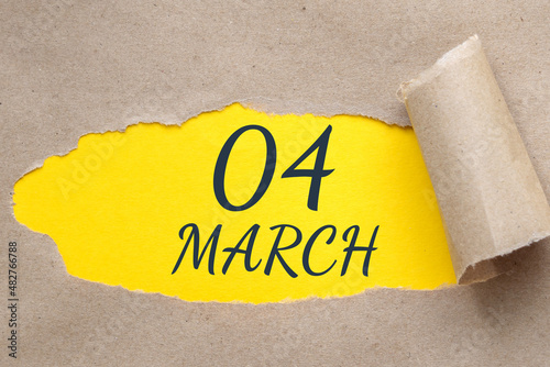 march 04. 04th day of the month, calendar date. Hole in paper with edges torn off. Yellow background is visible through ragged hole.Spring month, day of the year concept photo