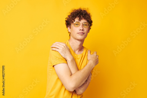 portrait of a young curly man wearing stylish glasses yellow t-shirt posing Lifestyle unaltered