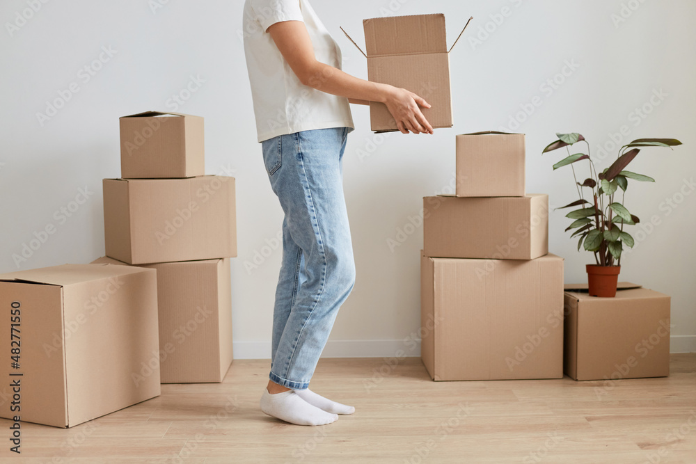 Portrait of unknown anonymous faceless woman wearing jeans moving new place, holding cardboard box with belongings, relocating, renting or buying new flat. Portrait of unknown anonymous faceless woman wearing jeans moving new place, holding cardboard box with belongings, relocating, renting or buying new flat.
