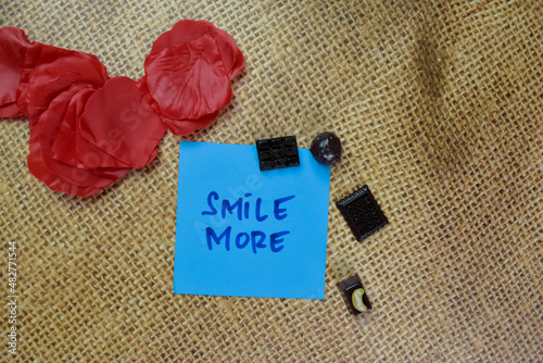 Smile More write on sticky notes isolated on Wooden Table.