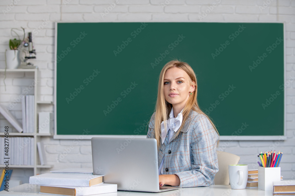 Young teacher. Portrait of young female college student studying in classroom on class with blackboard background. Young teacher. Portrait of young female college student studying in classroom on class with blackboard background.