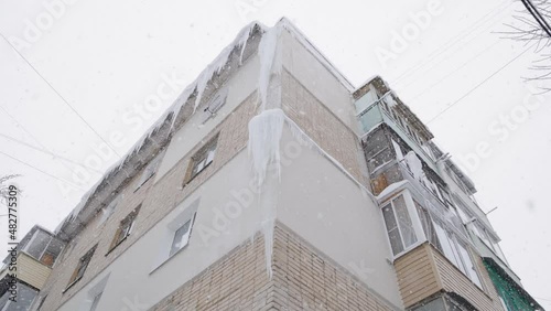 large isicles on russian chrushevka 5-storey building corner at winter day snowfall photo