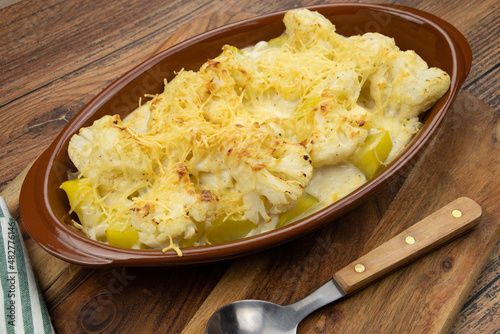 Cauliflower and potato gratin in a dish on a wooden board