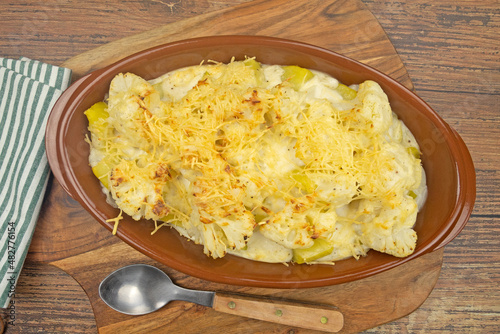 Cauliflower and potato gratin in a dish on a wooden board