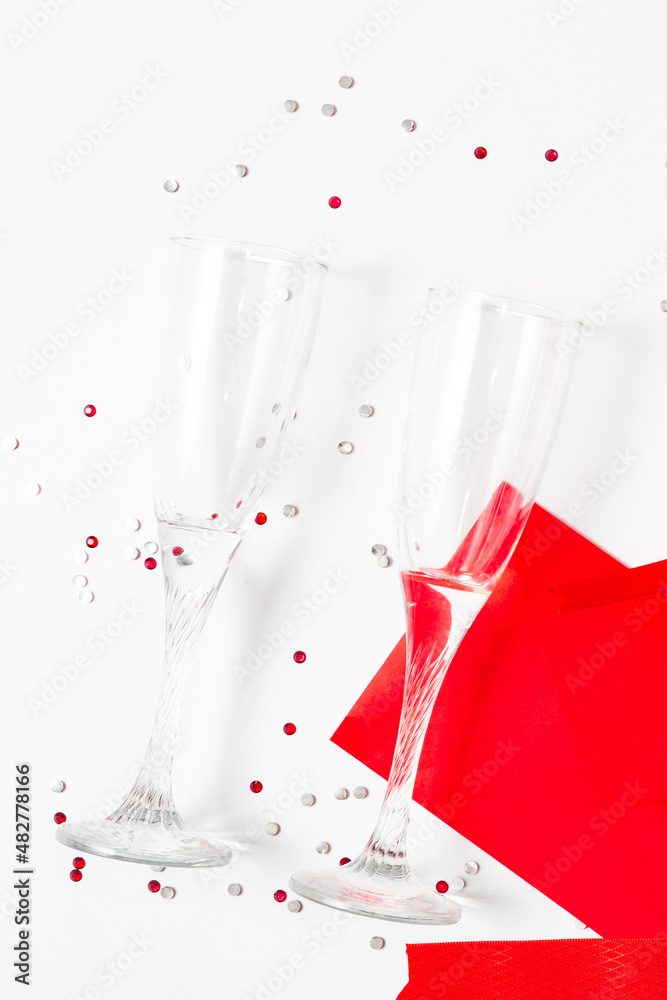 Flat lay two glasses and red envelope on white background. Valentines day celebration, romantic dinner couple concept Flat lay two glasses and red envelope on white background. Valentines day celebration, romantic dinner couple concept