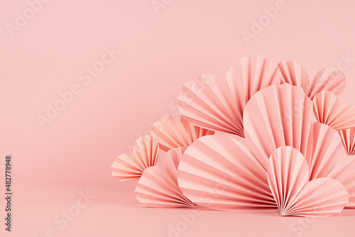 Valentines day scene in asian style - pink paper hearts of folded fans on pastel pink color  border  copy space  closeup. Romantic stage mockup for presentation cosmetic product  goods  card  poster.