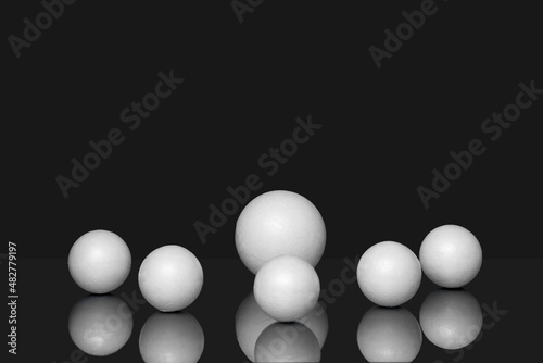 3d geometric shapes on black isolated background with reflection. White three-dimensional spheres  of different sizes  scattered in chaotic manner