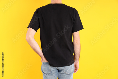 Man in blank black t-shirt on yellow background