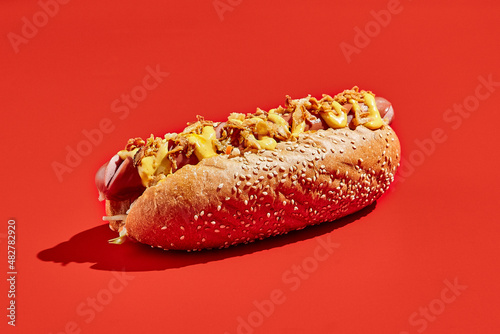 Billede på lærred American hot dog with cheese and crispy onion on red background minimal style