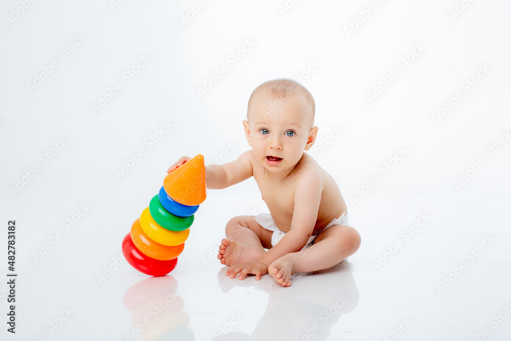 a little baby boy in a diaper is sitting on a white background playing a multi-colored pyramid , studio shooting a little baby boy in a diaper is sitting on a white background playing a multi-colored pyramid , studio shooting