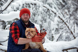 Happy man with lovely dog in snowy forest. Smiling boy going adorable puppy in winter wood. Pet lover. Dog - human s friend concept.