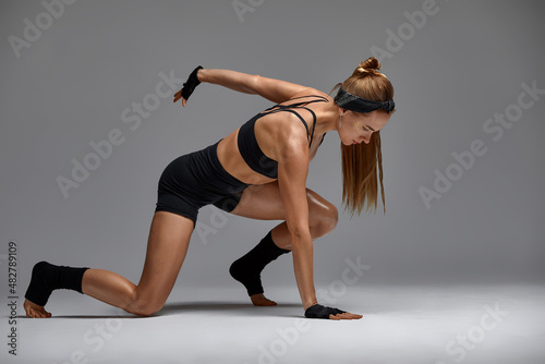 beautiful woman ballet dancer in black swimsuit posing on light grey studio background. Animal instinct