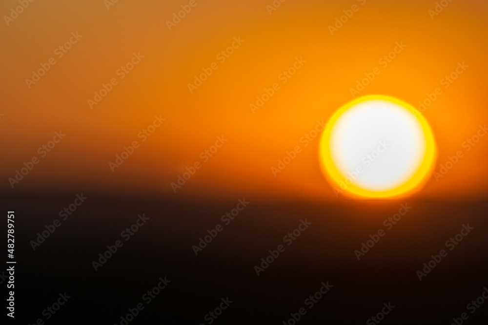Giant yellow and white globe of setting sun in abstract defocus