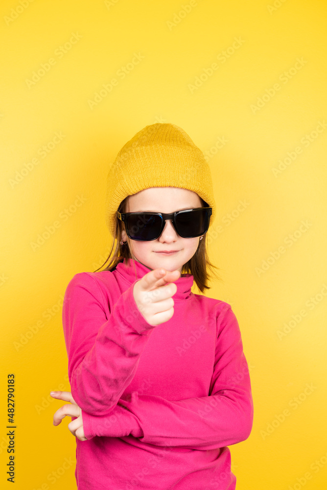 Child on winter clothes and sunglasses pointing to camera Child on winter clothes and sunglasses pointing to camera