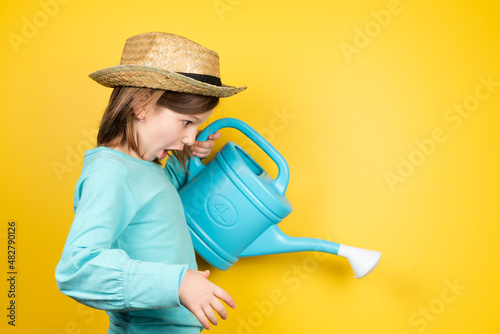 Surprised little gardener girl using a watering can