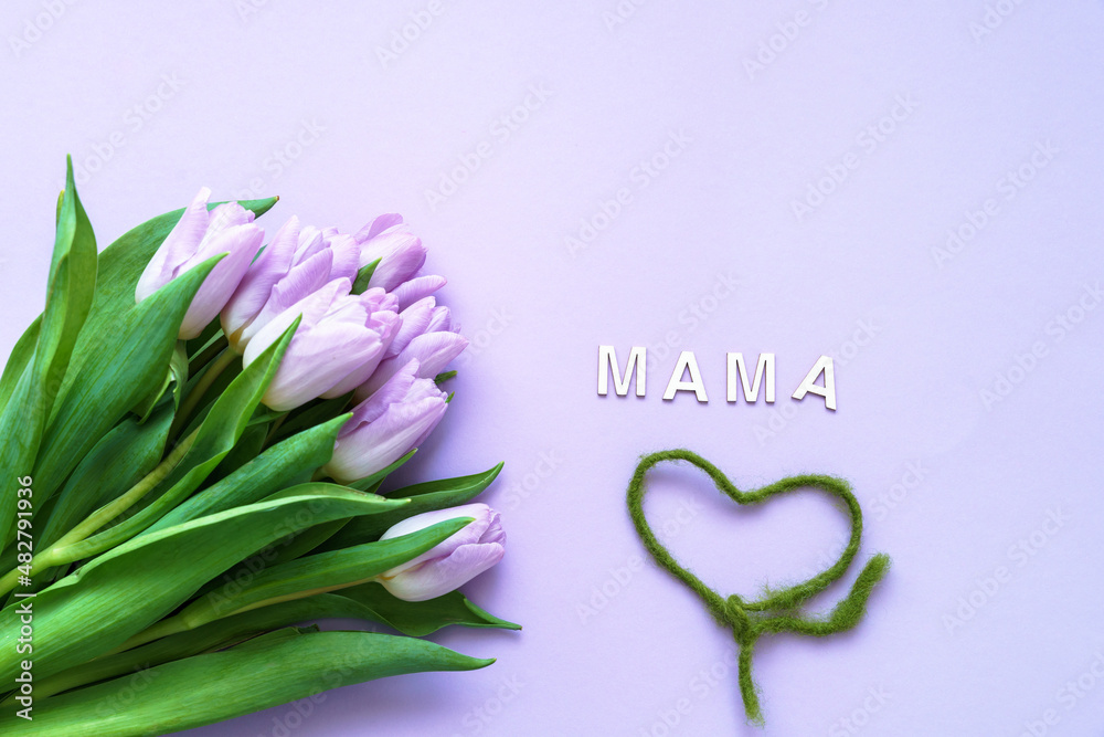 Ein Strauß lila Tulpen, eine grüne Kordel in Herzform und Mama in deutsch als Text auf einem lila Hintergrund. Flat lay, Muttertag.