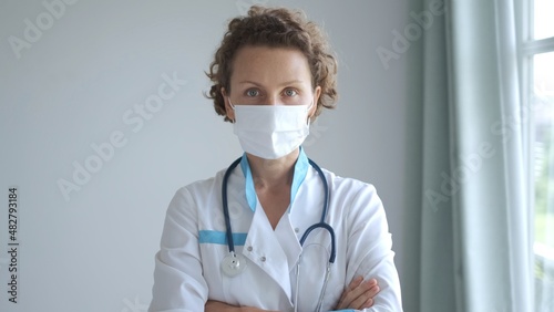 Serious concentrated female nurse or doctor looking at the camera, medical worker in mask on her work in hospital