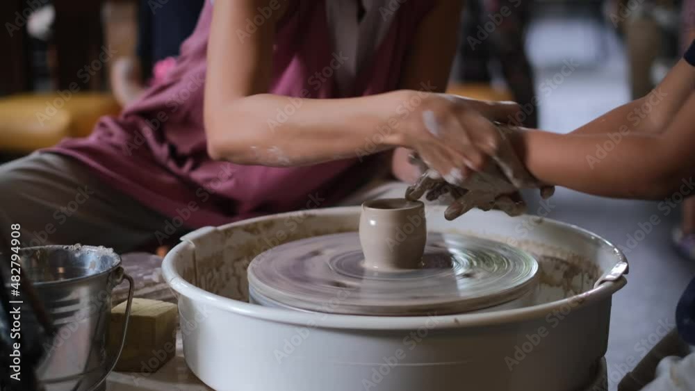 Art master teacher making pottery workshop for kids and preschoolers in art studio, rounding pottery spot.