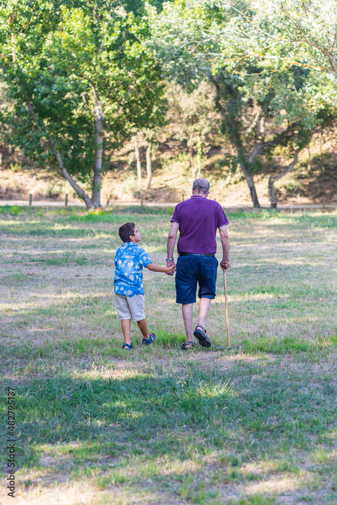 Obraz premium Little kid and elderly man walking in the field