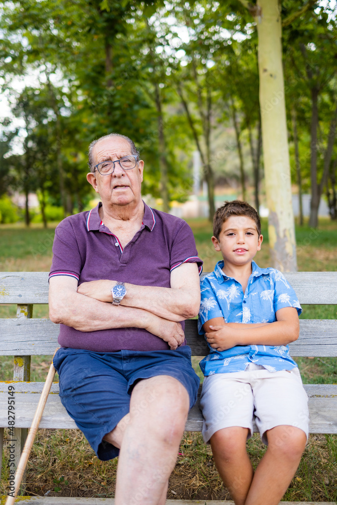 Grandfather and his grandson sitting on a bench in the park Grandfather and his grandson sitting on a bench in the park