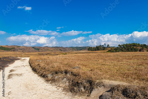 countryside fields with leading line of white sand bright and blue sky at morning from flat angle