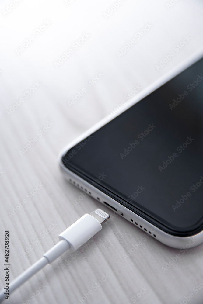 Mobile smart phone on wireless charging device on white background. Icon battery and charging progress lighting on screen.smartphones connected to power source.low battery level problems.Plugged Phone