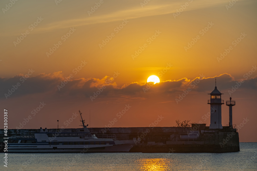 the sun rises from behind the Yalta lighthouse