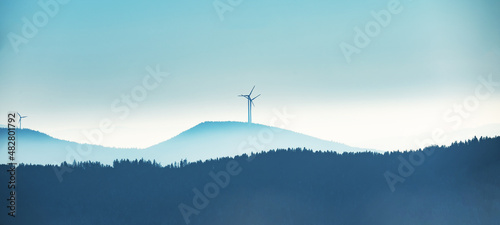 Black Forest background - Amazing blue foggy fog panorama landscape with silhouette from forest trees and pinwheels