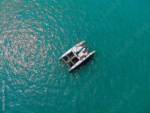 Bird's eyes view of the amazing white catamaran sailing across the blue lagoona. Top view. © Semachkovsky 