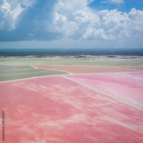 Pink lake with white salt near the shore. In the background, a salt factory against a blue sky. Las Coloradas, Yucatan, Mexico photo