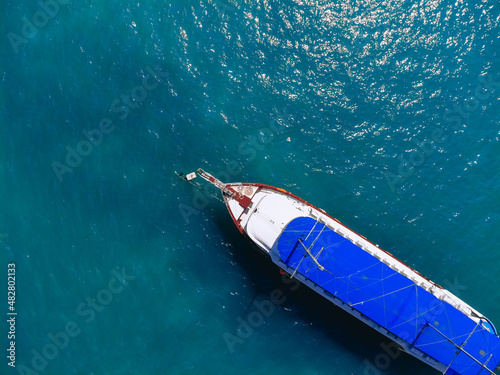 Top view of a huge white yacht with a blue roof is floating across the sea