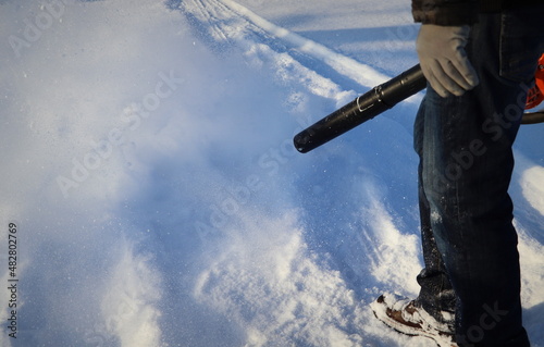 Man cleans pavement from snow with blower photo