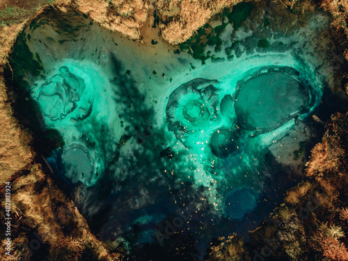 Amazing aerial view huge deep-sea picturesque emerald lake in the shape of a heart, located next to a dense forest filled with various tall trees