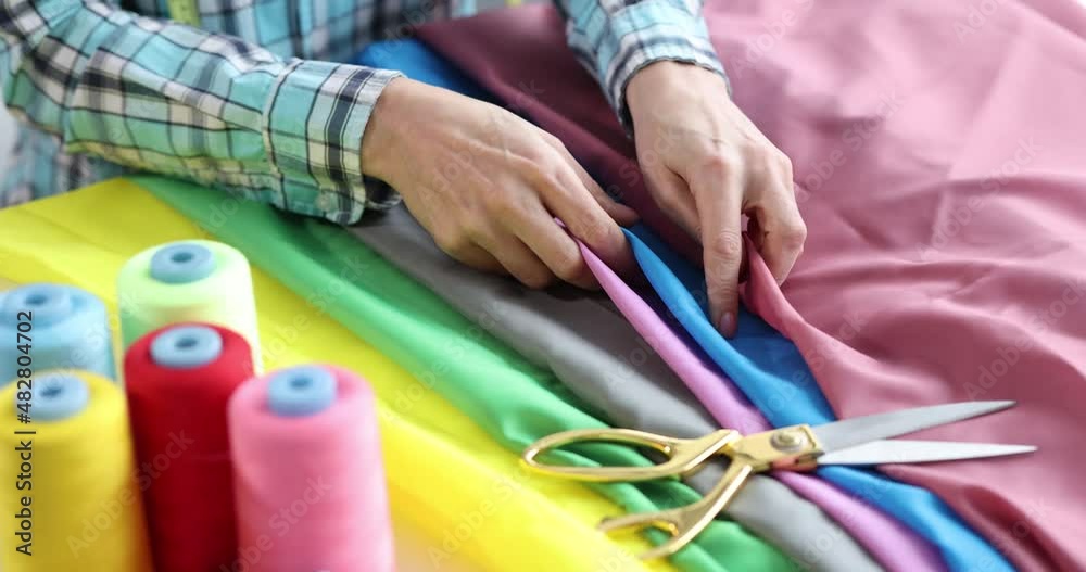 Seamstress chooses fabrics for tailoring collection of clothes closeup