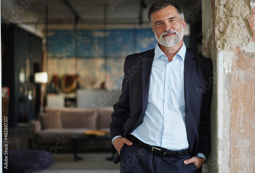 Canvas Print Positive confident mature executive man smiling and looking at camera while stan