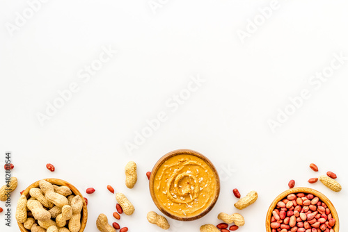 Creamy peanut butter and nuts in wooden bowls, top view