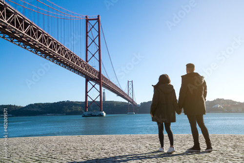 unrecognizable young couple on the 25th of april bridge, lisbon, portugal