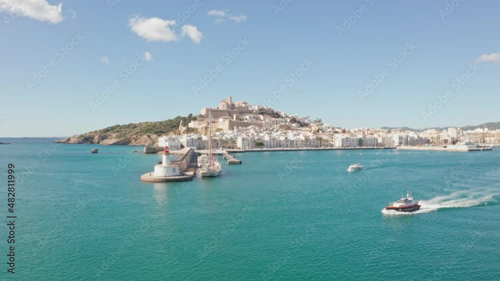Ibiza, Spain - Boat leaving port of Ibiza City Eivissa. Filmed by drone aerial. Ibiza City in background, ocean in foreground, bird flying trough Ibiza, Spain - Boat leaving port of Ibiza City Eivissa. Filmed by drone aerial. Ibiza City in background, ocean in foreground, bird flying trough