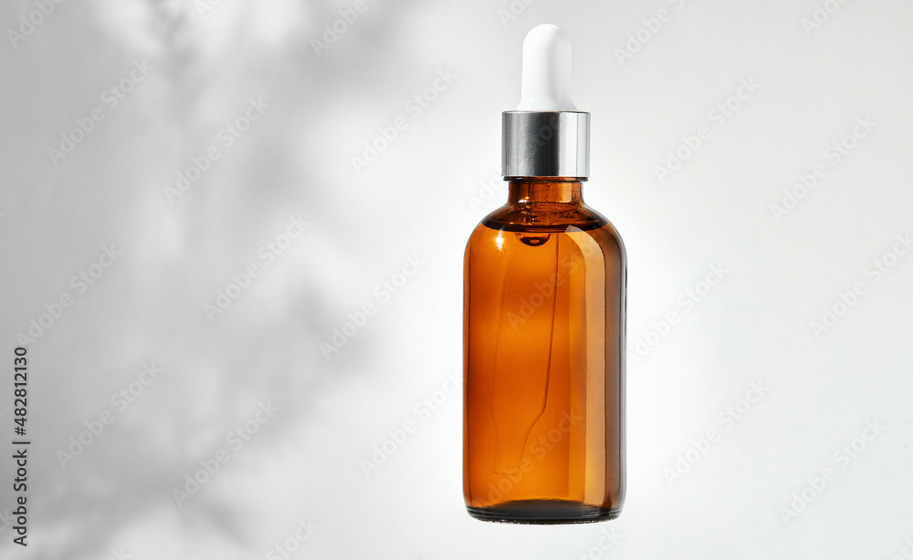 Essential oil in glass bottle with dropper isolated on a gray background with clipping path. Cosmetic medical beauty product for aromatherapy. Alternative medicine.
