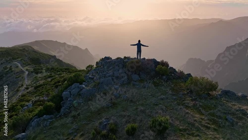 Man stands on top of mountain and looks at the sunrise sky. Aerial view of magnificent sunrise in the mountains of Madeira island. Climber in the mountains achieved his goal and enjoys wonderful