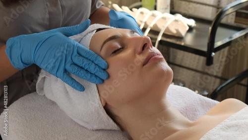 A young beautiful girl lies on the table at the beautician and receives procedures, a light massage, hands in blue gloves, the skin is smooth	  