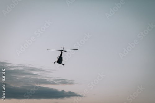Fototapeta Naklejka Na Ścianę i Meble -  Helicopter against the morning sky, some scattered clouds, emergency mission in progress; aerial vehicle concept.