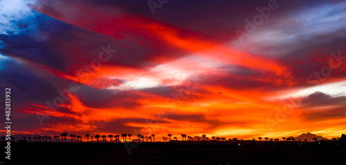 very beautiful orange  red  yellow and purple colors of the sunset sky with silhouettes of mountains and palms in egypt  sahl hashish