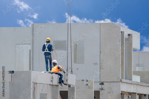 Construction worker are installing the precast concrete beam at housing estate, build a house, Worker wearing Safety Uniform, safety helmet and color vest.