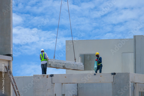 Construction worker are installing the precast concrete beam at housing estate, build a house, Worker wearing Safety Uniform, safety helmet and color vest.